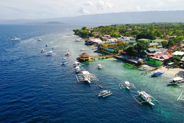 Aerial view of sandy beach with tourists swimming in beautiful clear sea water of the Sumilon island beach landing near Oslob, Cebu, Philippines. - Boost up color Processing.